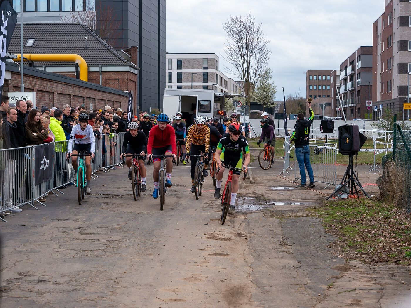 Riders in a cyclocross race on a muddy park course.